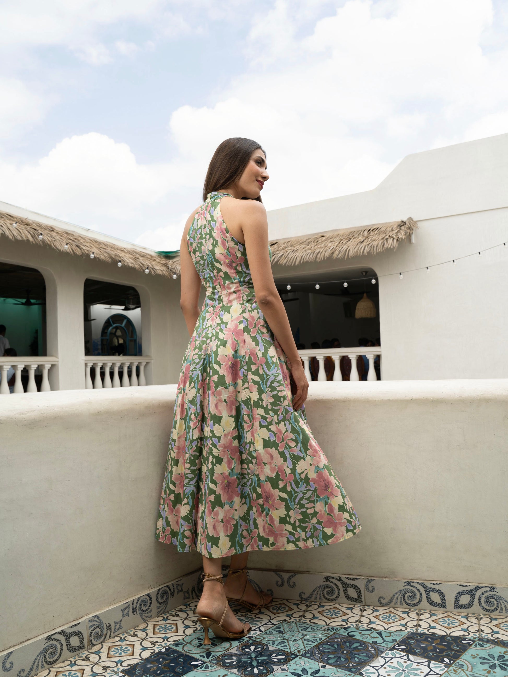 Side rear view of model wearing Hibiscus floral halter midi with covered buttons, open back, and fit-and-flare silhouette-MISSVI