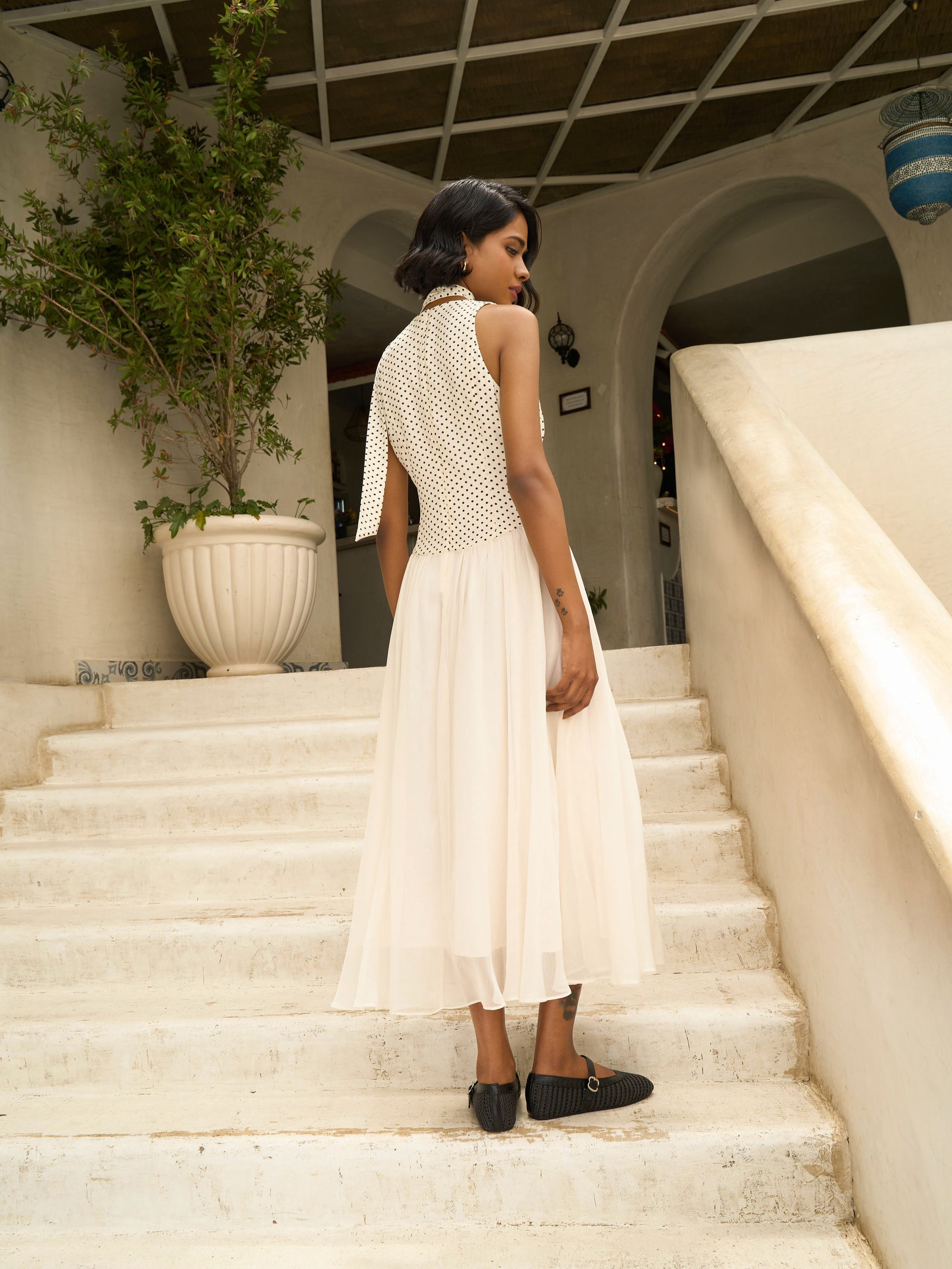 Rear side view of model wearing Apricot white midi dress with polka dot bodice, pleated skirt, and neck scarf-MISSVI