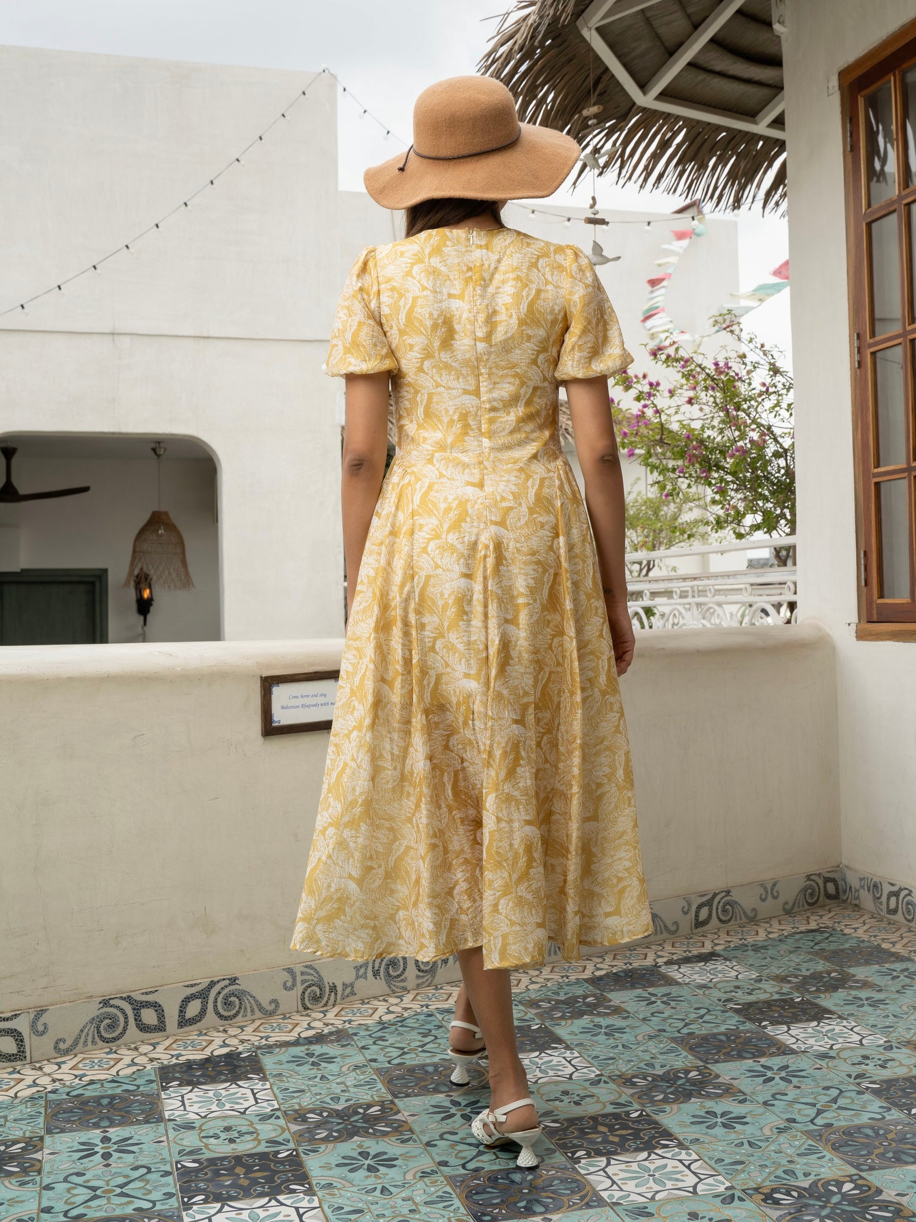 Rear view of model wearing yellow Floral fit-and-flare midi with puff sleeves, covered buttons, and V-neckline-MISSVI